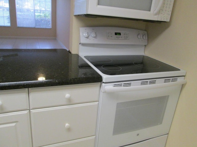 kitchen with white appliances, tile patterned flooring, and white cabinetry