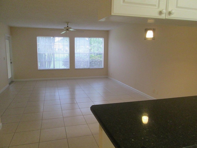 unfurnished room with light tile patterned flooring, a ceiling fan, and baseboards