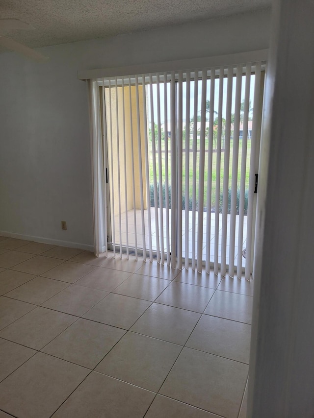 empty room with tile patterned floors, baseboards, and a textured ceiling