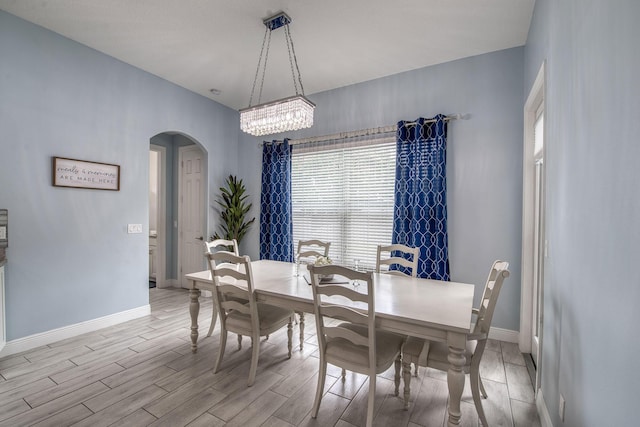 dining room with arched walkways, baseboards, and wood tiled floor