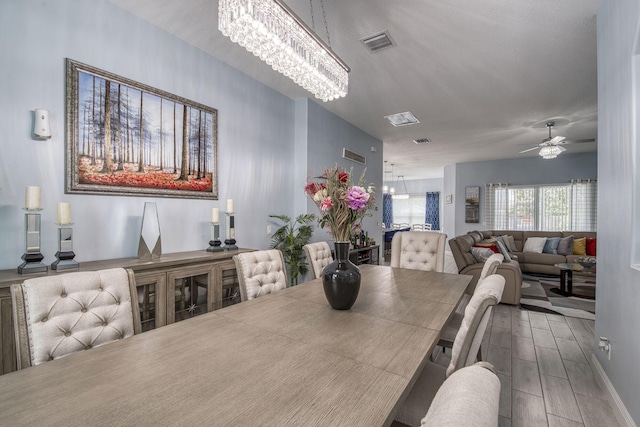 dining space with ceiling fan with notable chandelier, wood finished floors, and visible vents