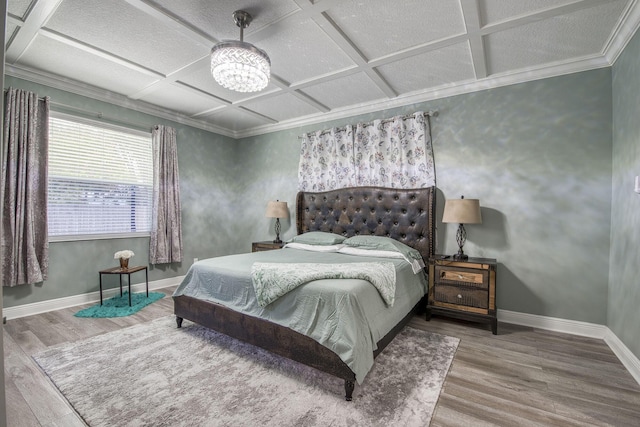 bedroom featuring a notable chandelier, baseboards, coffered ceiling, and wood finished floors