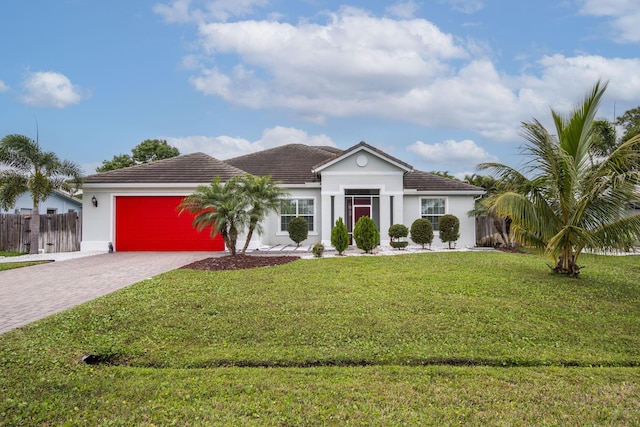 view of front of house with an attached garage, fence, decorative driveway, a front lawn, and stucco siding