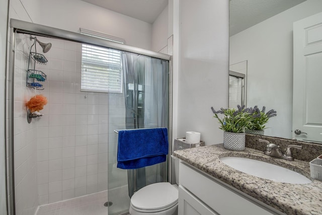 bathroom with toilet, a stall shower, and vanity