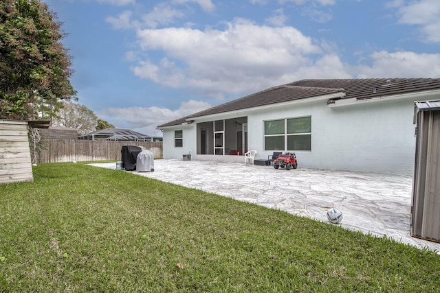 rear view of house with a yard, fence, a sunroom, and a patio