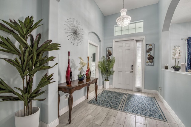 foyer entrance featuring wood finish floors, arched walkways, and baseboards