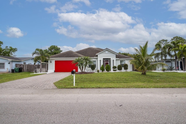 view of front of home featuring a front yard, decorative driveway, fence, and an attached garage