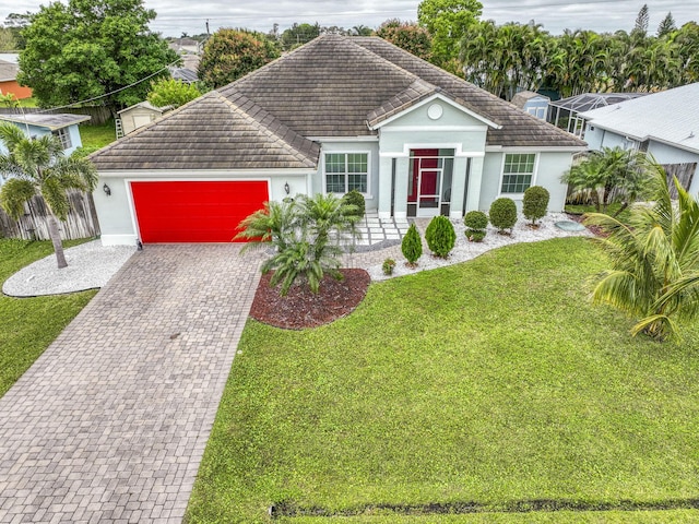 single story home with a garage, a tiled roof, decorative driveway, stucco siding, and a front lawn