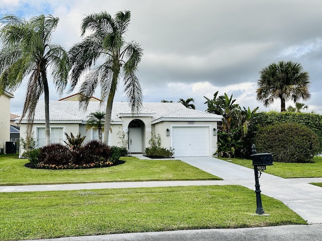 view of front of property featuring a garage, driveway, a front lawn, and stucco siding