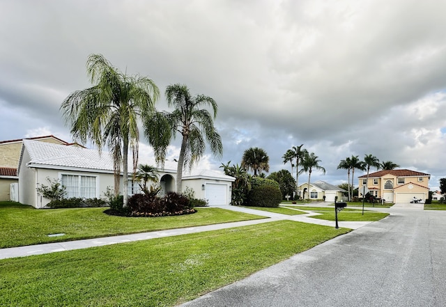 view of front of property with driveway, a front lawn, a residential view, and stucco siding