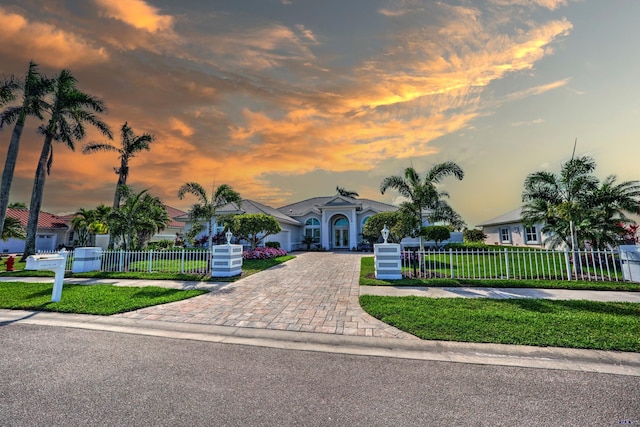 view of front facade with driveway, a fenced front yard, a residential view, and a front lawn