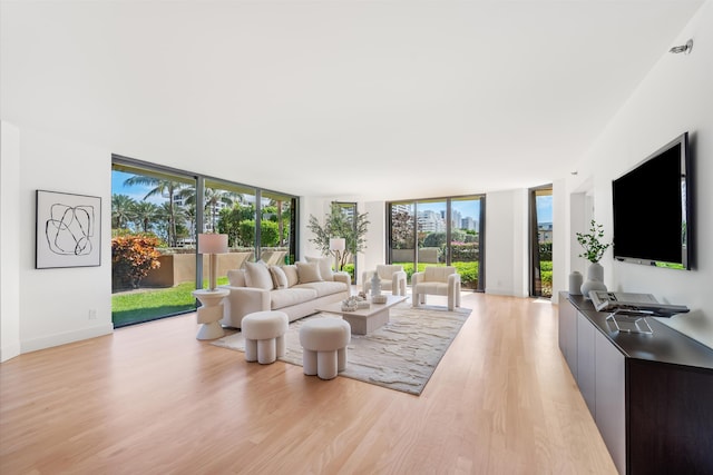 living area featuring baseboards, light wood finished floors, and floor to ceiling windows