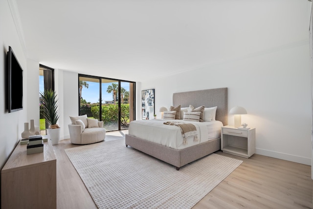 bedroom featuring baseboards, access to outside, wood finished floors, and floor to ceiling windows