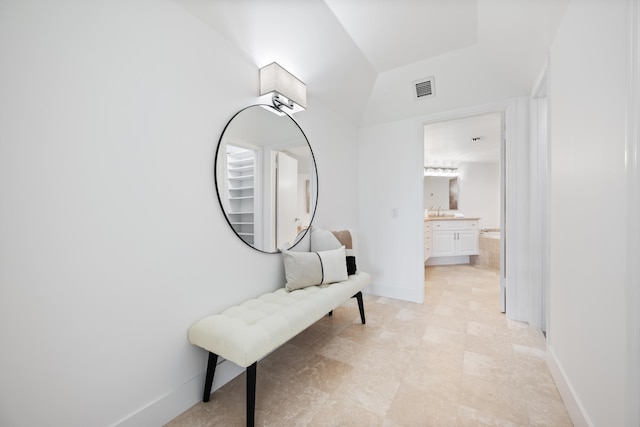 hallway with baseboards, visible vents, and a sink