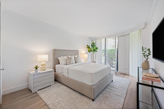 bedroom featuring light wood finished floors, baseboards, access to exterior, and ornamental molding