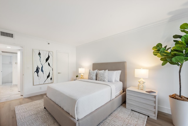 bedroom with ornamental molding, visible vents, and light wood-style floors