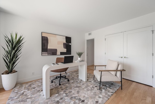 office space featuring visible vents, light wood-style flooring, and baseboards