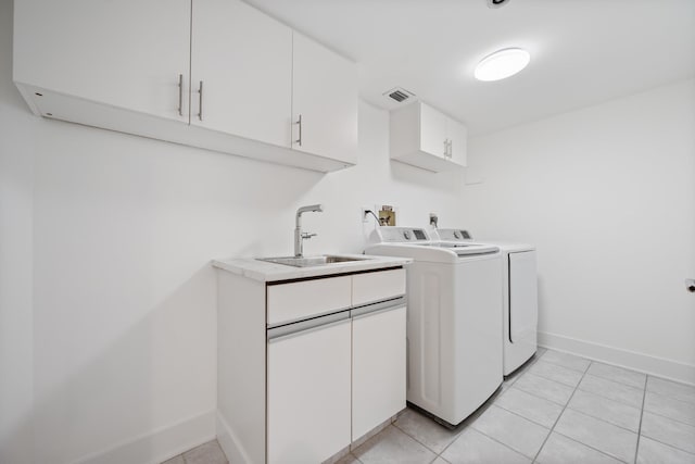 washroom with cabinet space, baseboards, visible vents, washing machine and clothes dryer, and a sink