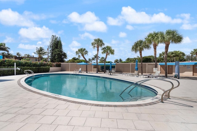 community pool with a patio area and fence