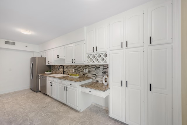 kitchen with white cabinetry, appliances with stainless steel finishes, a sink, and stone countertops