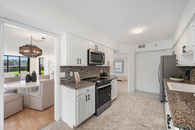 kitchen with stainless steel appliances, a sink, visible vents, white cabinetry, and hanging light fixtures