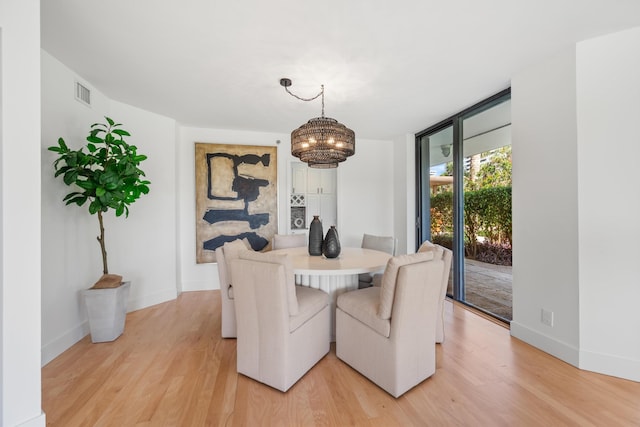 dining room featuring baseboards, floor to ceiling windows, visible vents, and light wood-style floors