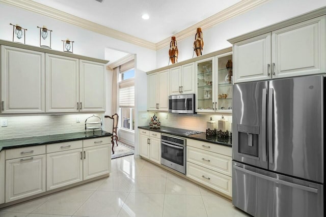 kitchen featuring dark countertops, appliances with stainless steel finishes, glass insert cabinets, and light tile patterned flooring