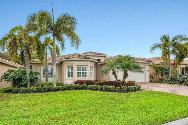 view of front of home with decorative driveway, a tile roof, stucco siding, a front yard, and a garage