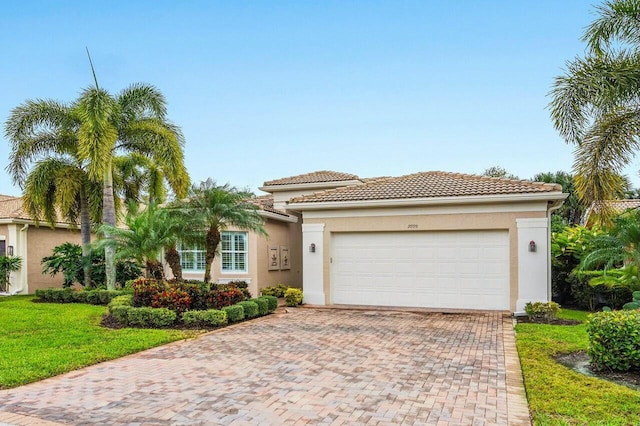 view of front facade featuring decorative driveway, an attached garage, a tile roof, and stucco siding