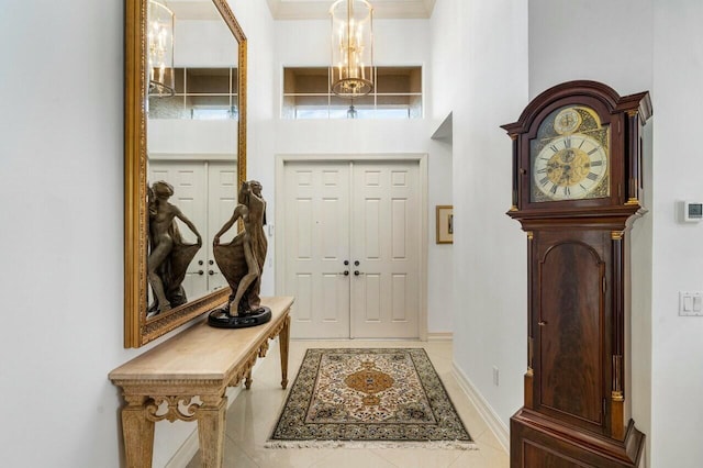 entryway with light tile patterned floors, a notable chandelier, and baseboards