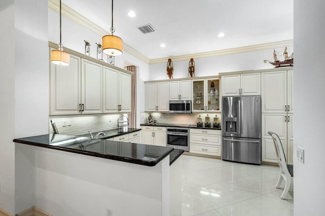 kitchen with a peninsula, hanging light fixtures, appliances with stainless steel finishes, dark countertops, and glass insert cabinets