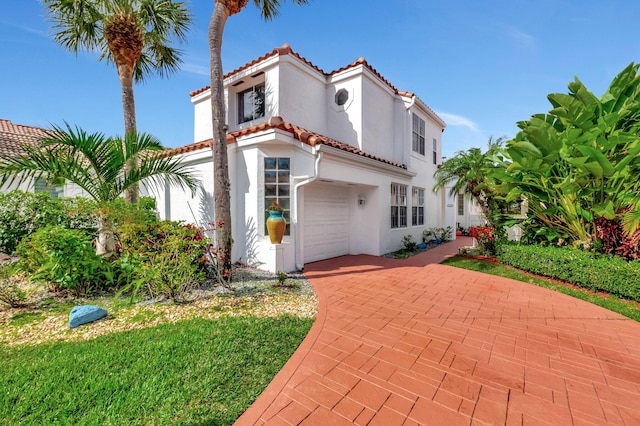 mediterranean / spanish home with a tiled roof, an attached garage, and stucco siding