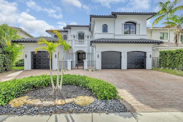 mediterranean / spanish-style home featuring a garage, decorative driveway, a tile roof, and stucco siding