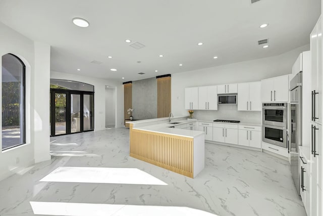 kitchen featuring black gas cooktop, a peninsula, a sink, white cabinets, and marble finish floor