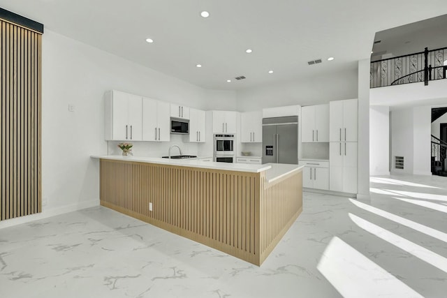 kitchen featuring a peninsula, white cabinetry, light countertops, and built in appliances