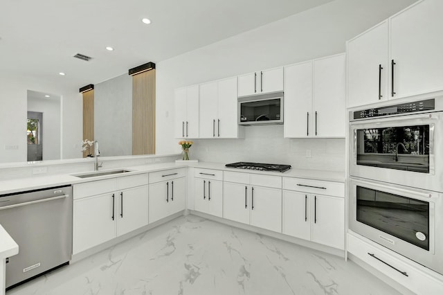 kitchen with stainless steel appliances, white cabinets, light countertops, and a sink