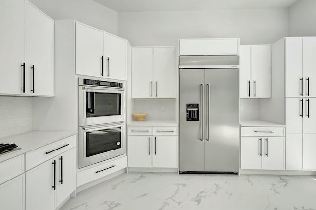 kitchen with stainless steel appliances, light countertops, backsplash, and white cabinetry