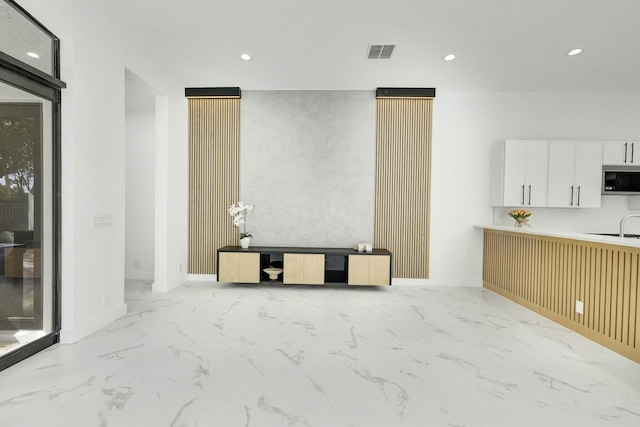 unfurnished living room with baseboards, marble finish floor, visible vents, and recessed lighting