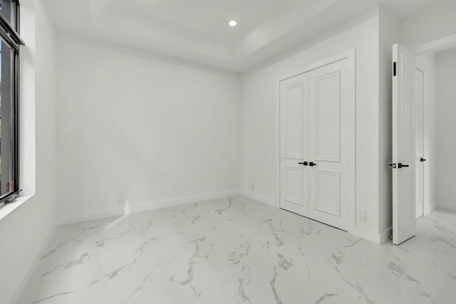 unfurnished bedroom featuring a closet, recessed lighting, marble finish floor, and baseboards