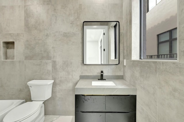 bathroom with marble finish floor, vanity, toilet, and tile walls