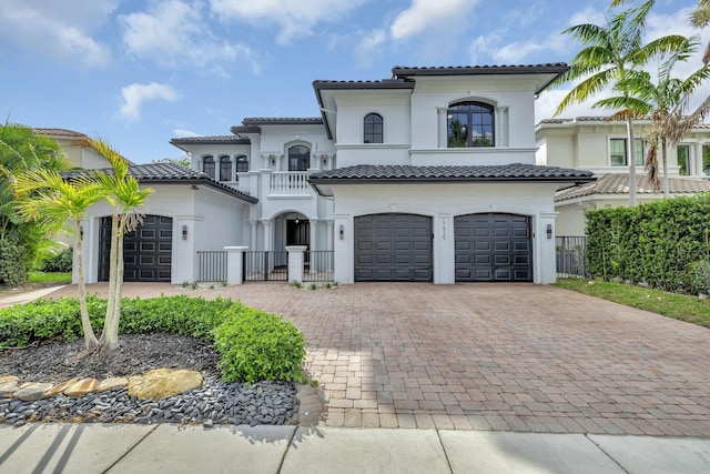 mediterranean / spanish home with decorative driveway, a tile roof, and stucco siding