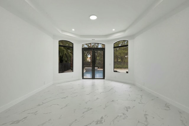 unfurnished room featuring french doors, recessed lighting, a raised ceiling, and baseboards