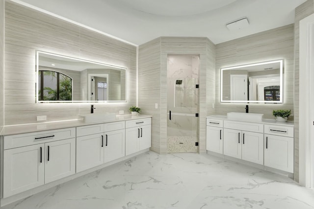 bathroom with marble finish floor, a stall shower, a sink, and tile walls