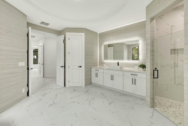 bathroom with visible vents, vanity, tile walls, marble finish floor, and a marble finish shower