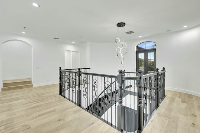 hallway featuring light wood-style floors, recessed lighting, visible vents, and an upstairs landing