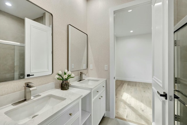 bathroom with recessed lighting, wood finished floors, a sink, and double vanity