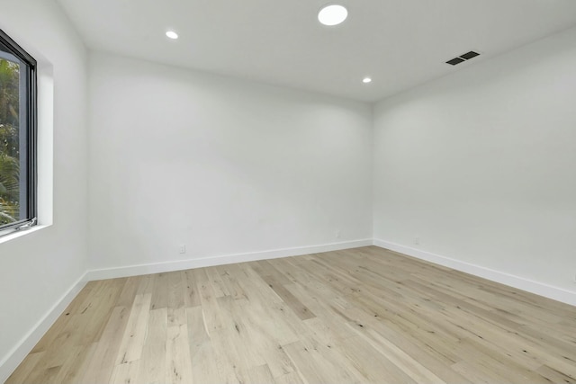 spare room with light wood-type flooring, baseboards, visible vents, and a wealth of natural light