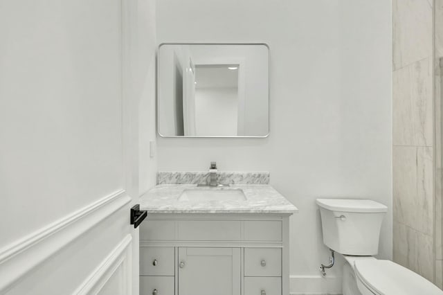 bathroom featuring toilet, baseboards, and vanity