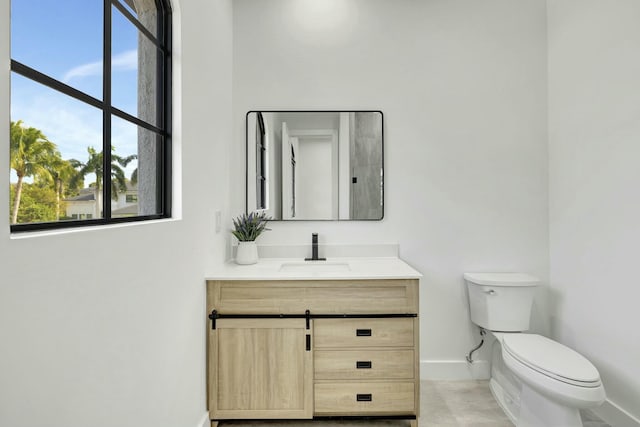 bathroom featuring toilet, vanity, and baseboards