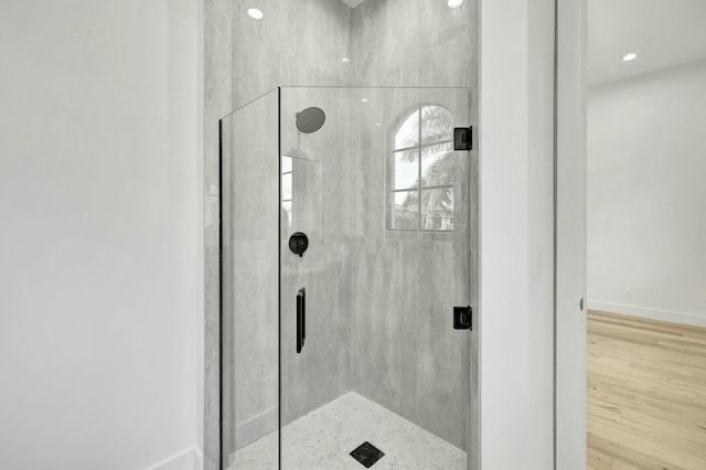 bathroom featuring a stall shower, wood finished floors, and baseboards